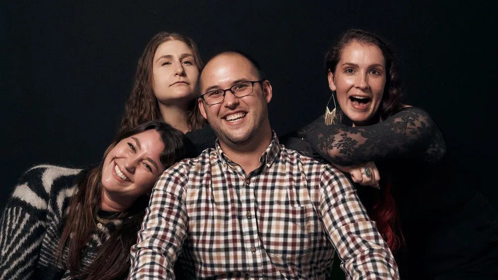 A group of people posing for a picture with one man wearing glasses